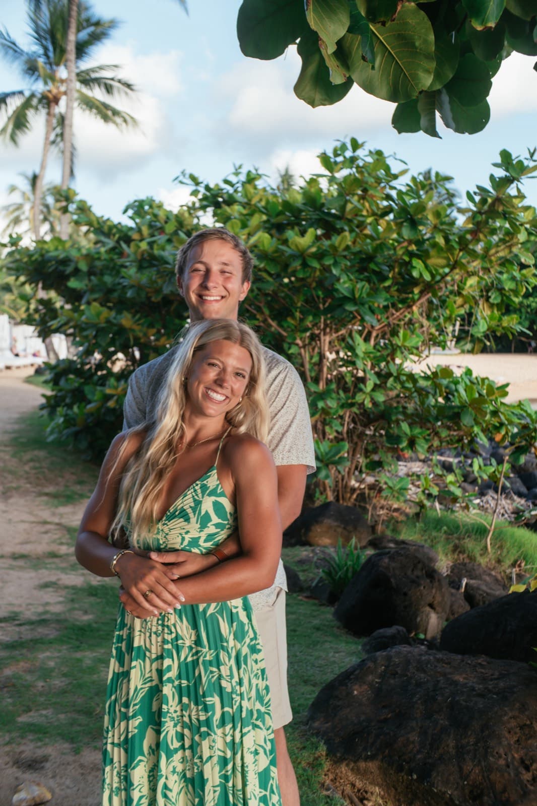 Will and Emma hugging on a sandy path, smiling at the camera